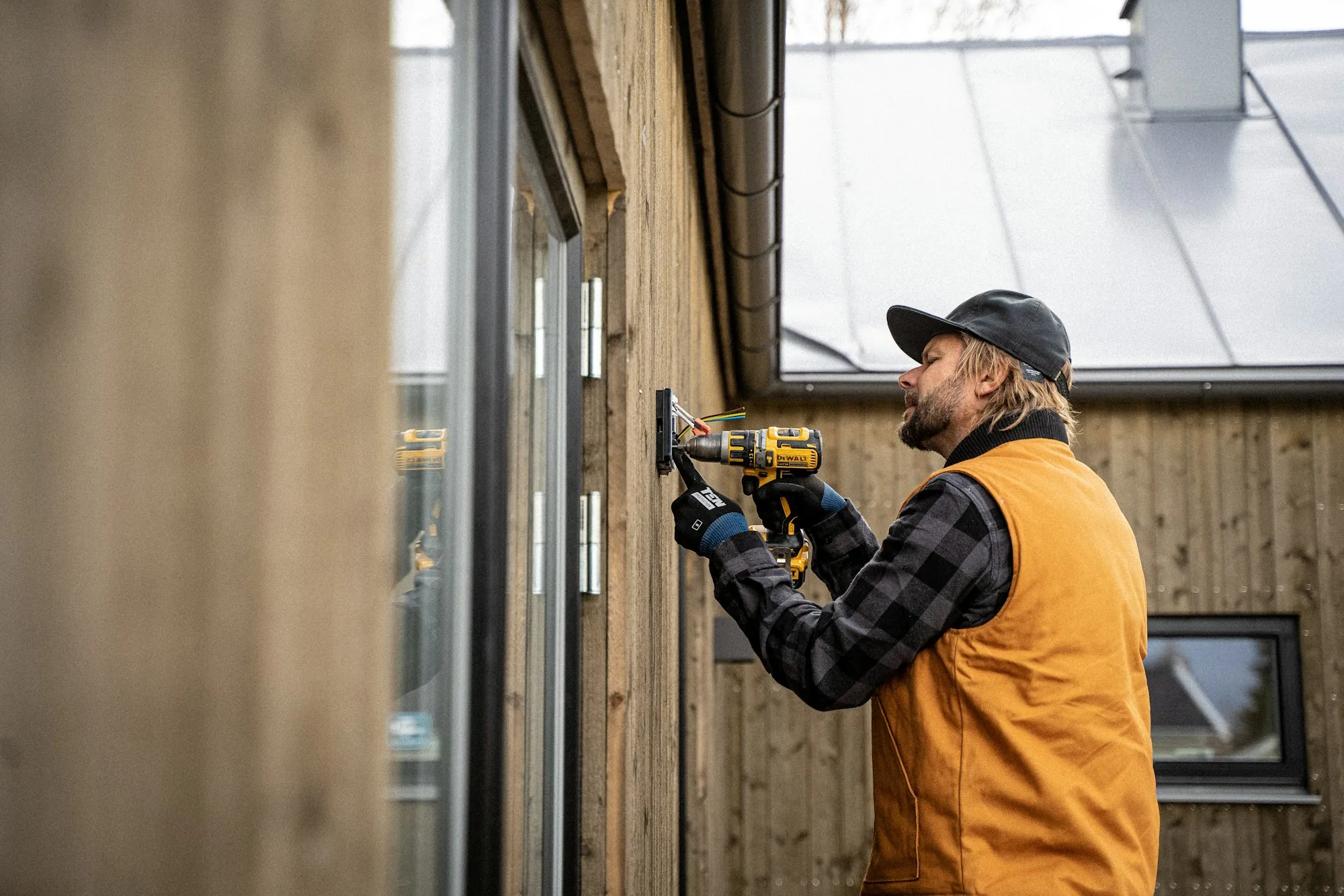 A tradesperson working with a drill on the exterior of a building