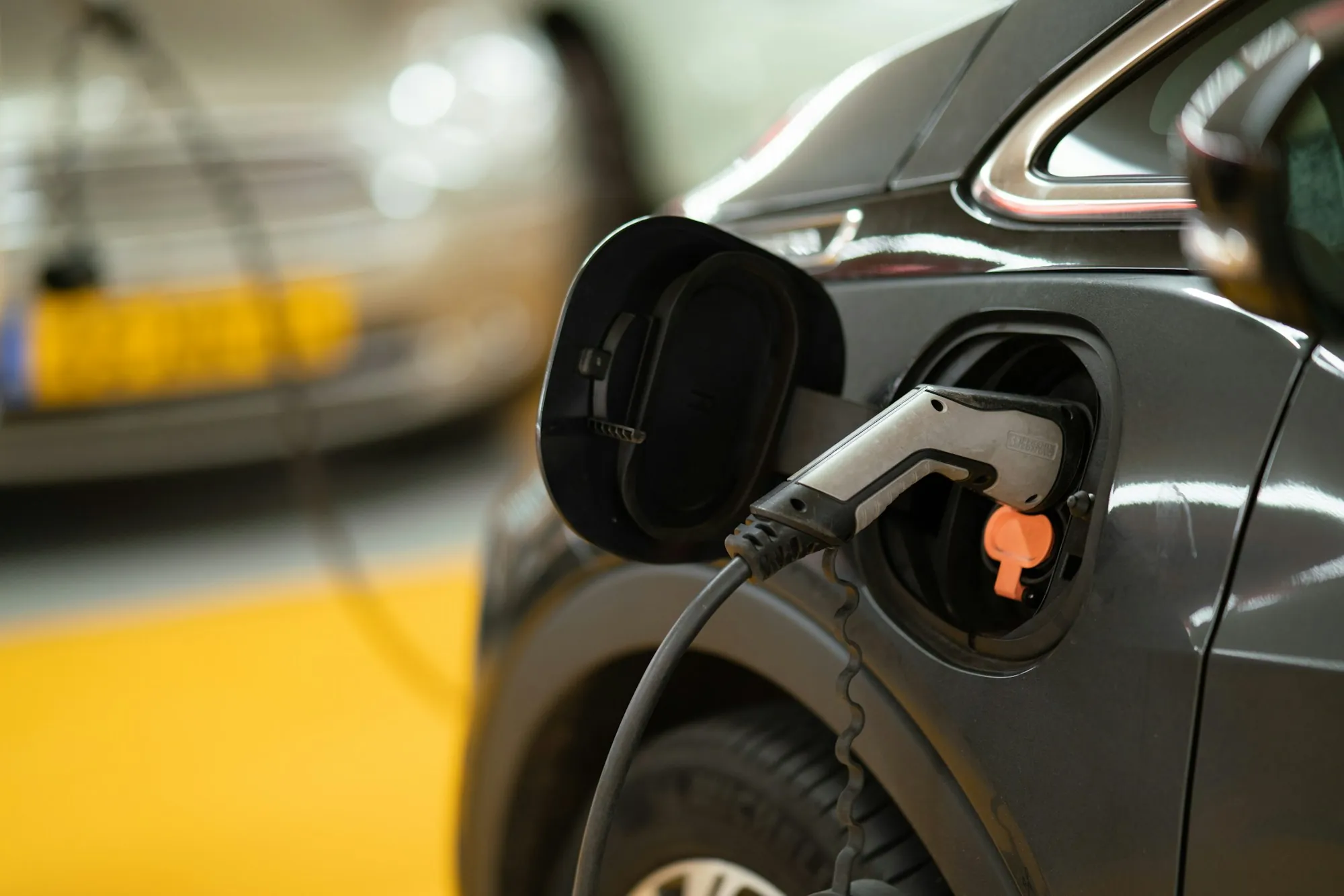 Charging plug seated in the port of a dark gray car in a garage